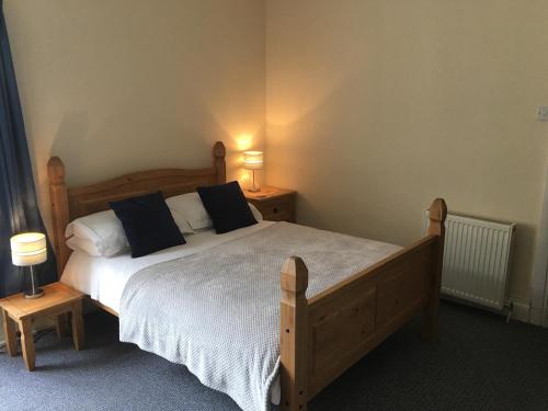 a bedroom with a large wooden bed with two night stands at Camelot Seafront Hotel in Blackpool