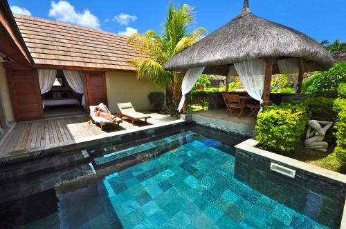 a swimming pool next to a house with a hut at Oasis Villas by Fine & Country in Grand Baie