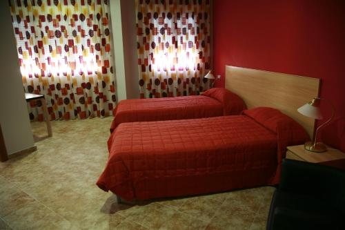 um quarto de hotel com duas camas e uma parede vermelha em HOSTAL EL POLIGONO em La Roda