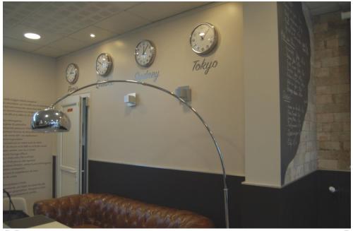 a room with a couch and clocks on the wall at La Caroline in Corbie