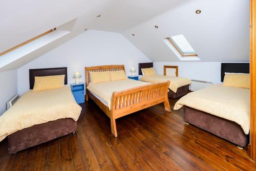 ディングルにあるDingle Centre Townhouse An Capall Dubh Dingleのウッドフロアの客室で、ベッド3台が備わります。