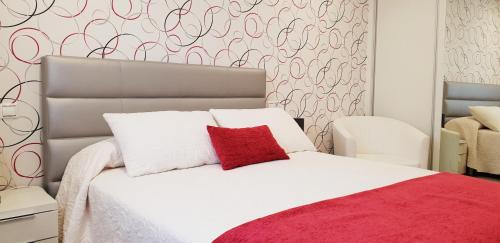 1 dormitorio con cama blanca y almohada roja en BALEA 62, en O Grove