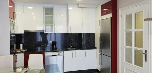 uma cozinha com armários brancos e um frigorífico em BALEA 62 em O Grove