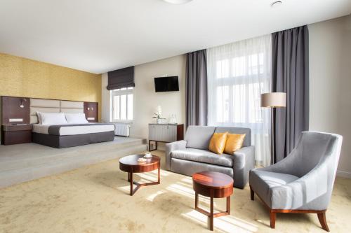 um quarto de hotel com uma cama, um sofá e uma cadeira em Jakubowy Hotel em Gdynia