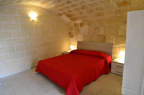 a bedroom with a red bed in a stone wall at Dimora Arco Antico in Monopoli