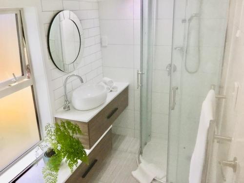 a bathroom with a sink and a shower with a mirror at G- HOUSE (CH-CH) in Christchurch