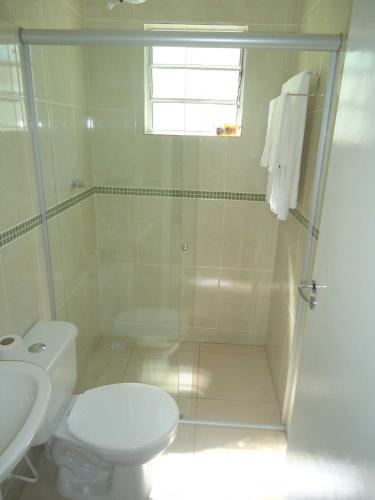 a white bathroom with a shower and a toilet at Pousada Clariô in Bertioga