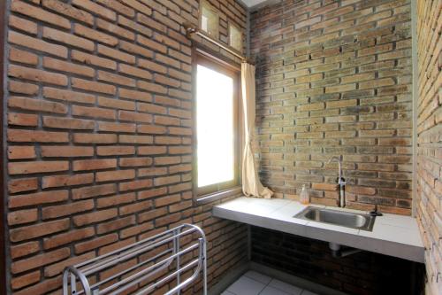 Baño con paredes de ladrillo, lavabo y ventana en Disaster Oasis en Kaliurang