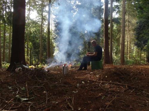 a man sitting next to a fire in a forest at The Old Three Pigeons in Nesscliffe