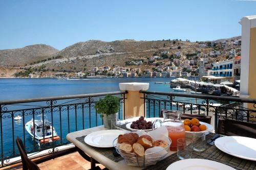 a table with food on a balcony with a view of the water at SeaMe Houses in Symi