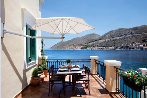 a table and chairs on a balcony with a view of the water at SeaMe Houses in Symi
