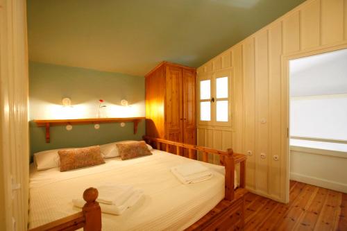 sypialnia z łóżkiem z drewnianym zagłówkiem i oknem w obiekcie SeaMe Houses w mieście Simi