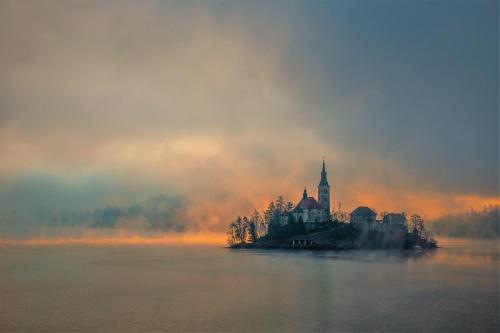 an island in the middle of a lake with a castle at Jazz Bled B&B in Bled