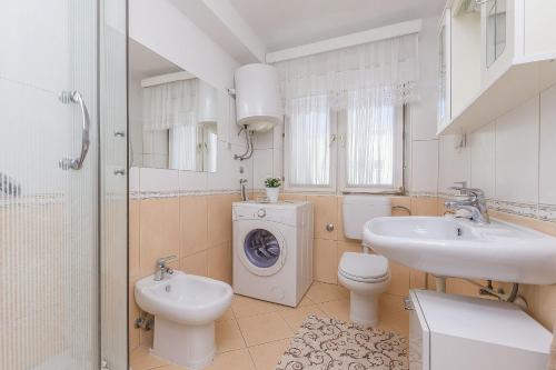 a bathroom with a sink and a washing machine at Apartment Nansy in Omiš