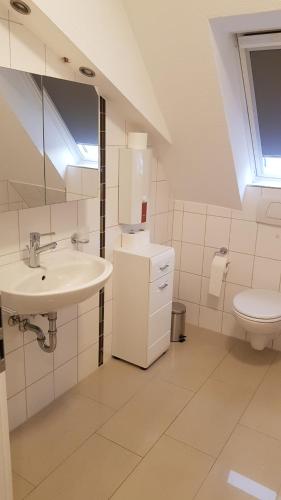a white bathroom with a sink and a toilet at Ferienwohnung in Freimersheim