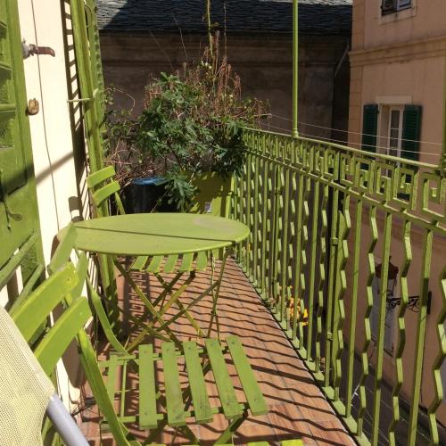 a green table and chairs on a balcony at La Marquise in Bastia