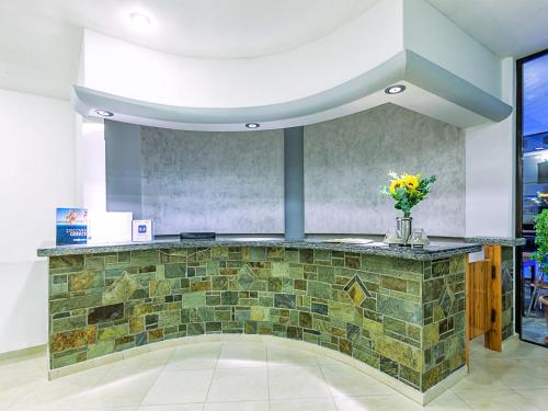 a lobby with a stone counter with a vase of flowers at Xenios Dolphin Beach Hotel in Possidi