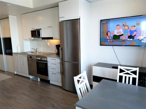 a kitchen with a refrigerator and a tv on the wall at Pro Apartments 4 in Vaasa