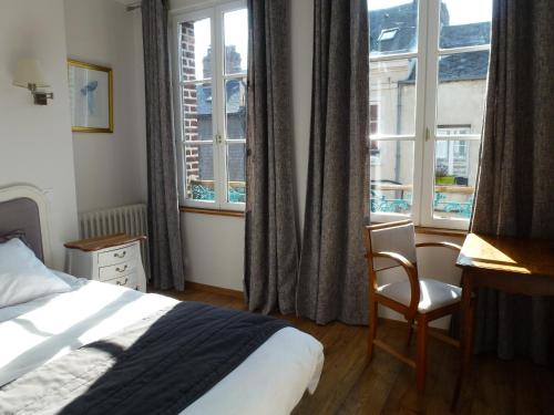 a bedroom with a bed and a desk and windows at Le Charme à la Française in Honfleur