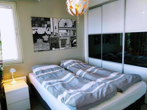 a bedroom with a bed with striped sheets and a chandelier at Pro Apartments 4 in Vaasa