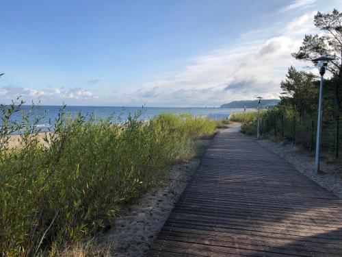 a wooden path next to a beach with the ocean at Blue Sea Apartment in Międzyzdroje