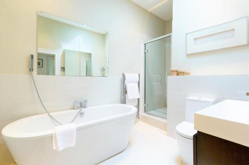 uma casa de banho branca com uma banheira e um lavatório em Queens Circus - Montpellier, Central Cheltenham em Cheltenham