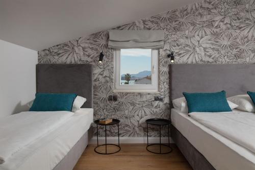 una camera con 2 letti con cuscini blu e una finestra di Pansion Amigos a Podstrana
