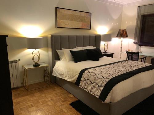 a bedroom with a bed with two lamps and two tables at Charming House Portas da Maia in Maia