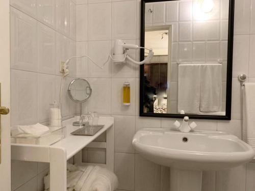 a white bathroom with a sink and a mirror at Charming House Portas da Maia in Maia