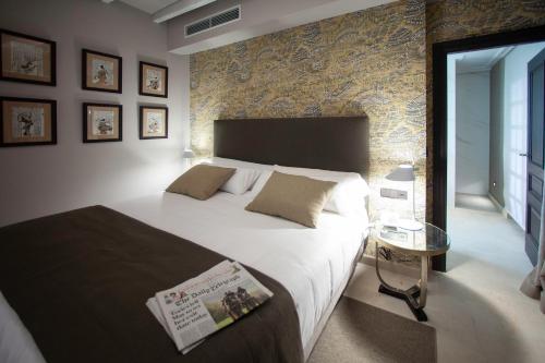 a bedroom with a large bed and a stone wall at Palacete Colonial in León