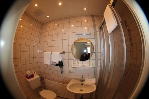 Ein Mann, der ein Bild von einem Badezimmer mit einem Spiegel macht. in der Unterkunft Hotel Stadt Munster in Munster im Heidekreis