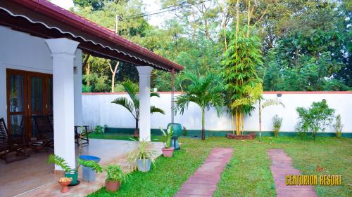 Un jardín con palmeras y una valla. en Centurion Resort, en Habarana