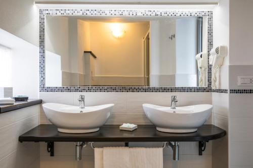 a bathroom with two sinks and a large mirror at Hotel La Playa in Cala Gonone