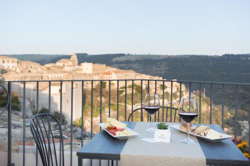 uma mesa azul com copos de vinho e comida numa varanda em Evoca em Ragusa