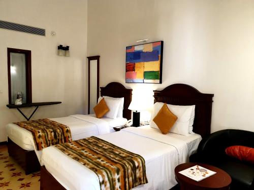 a hotel room with two beds and a couch at Novotel Goa Dona Sylvia Resort in Cavelossim