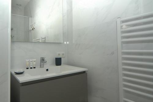 a white bathroom with a sink and a mirror at La Promenade Le Normandy 54-201 in Cadzand