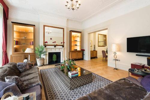 a living room with a couch and a fireplace at Grand Ambassadorial Duplex Apartment Hyde Park in London