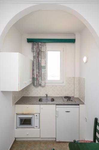 a white kitchen with a sink and a window at Polemis Studios & Apartments in Agia Anna Naxos