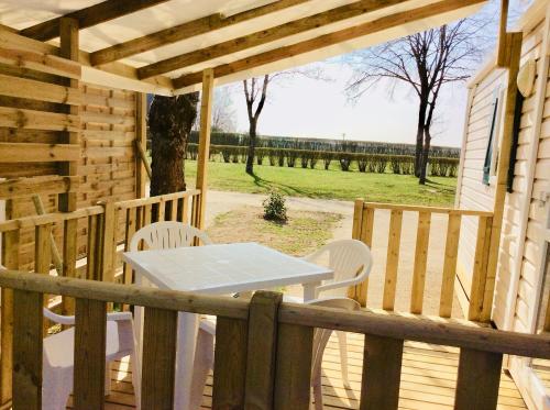 porche de madera con mesa blanca y sillas en Camping de Contrexeville, en Contrexéville