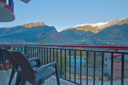 a balcony with two chairs and a view of mountains at Hotel Rockland Inn in Manāli