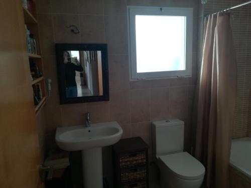 a bathroom with a sink and a toilet and a window at Casa Rufas in Altea