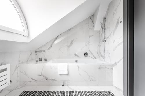 a white bathroom with a tub and a shower at Jakubowy Hotel in Gdynia