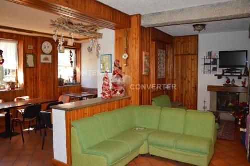 ein Wohnzimmer mit einem grünen Sofa und einem Tisch in der Unterkunft Albergo Sella - Monte Amiata in Abbadia San Salvatore