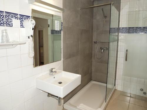 a white bathroom with a sink and a shower at Hotel Mar Azul in Lagos