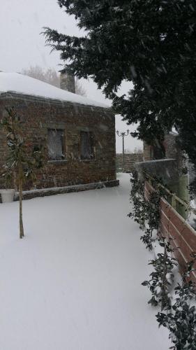 a snow covered yard with a brick building at Pacithea Villas in Miléai