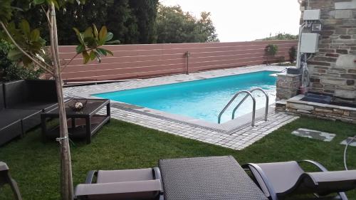 a swimming pool in a yard with chairs and a fence at Pacithea Villas in Miléai