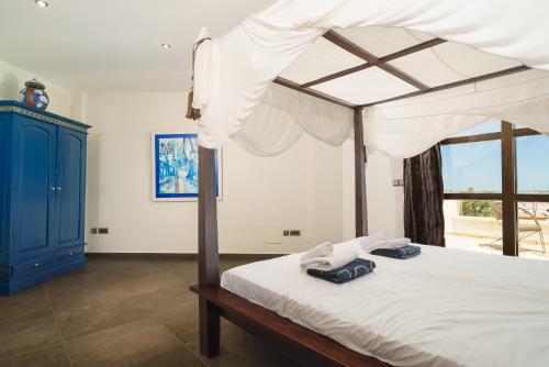 a bedroom with a canopy bed and a blue cabinet at Daru Dunya in Beniarbeig