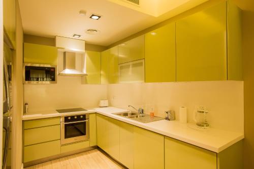 a yellow kitchen with yellow cabinets and a sink at Accra Fine Suites - The Pearl In City in Accra