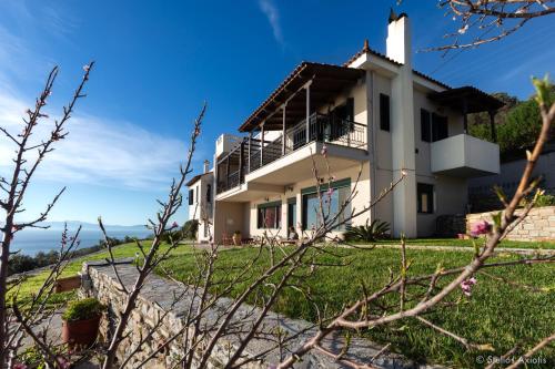 Biały dom na zielonym polu w obiekcie Aegean Panorama Apartments w mieście Akhladherí