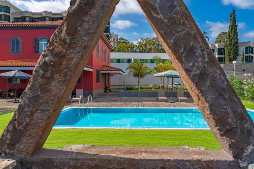 a pool in front of a red building at Century House with private pool by HR Madeira in Funchal